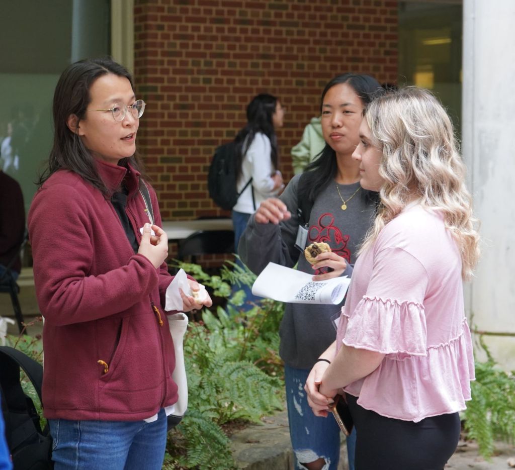 Professor Li talks with two undergraduate students.