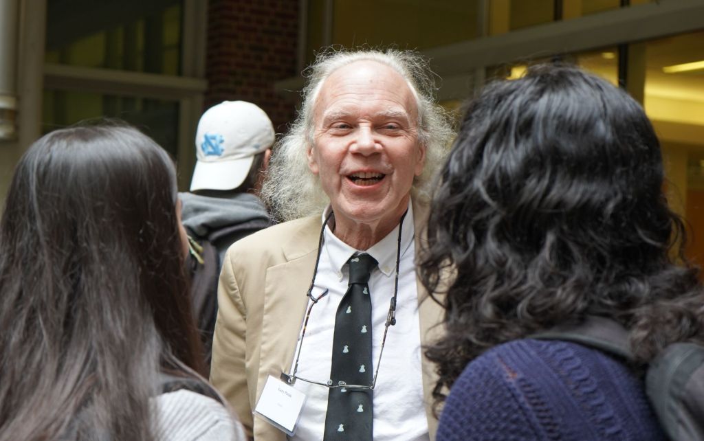 Professor Pielak smiles at two students while speaking with them.