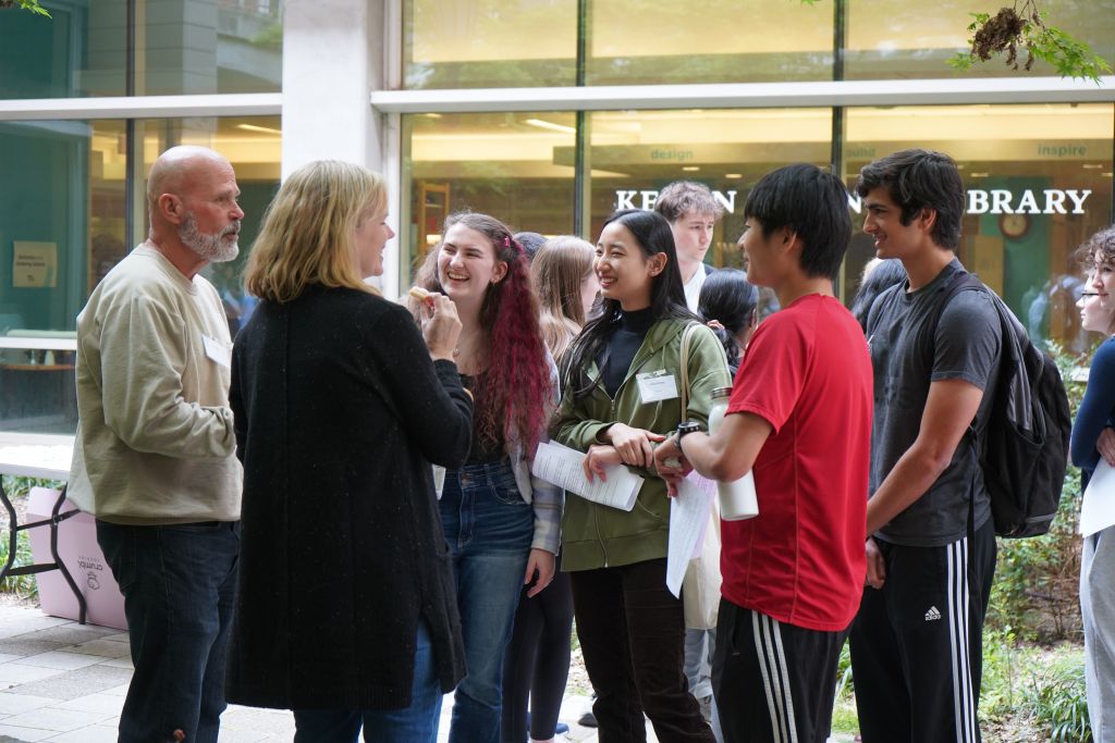 Professor Glish and Professor Baker smile and laugh with a group of students in front of the Kenan Library.